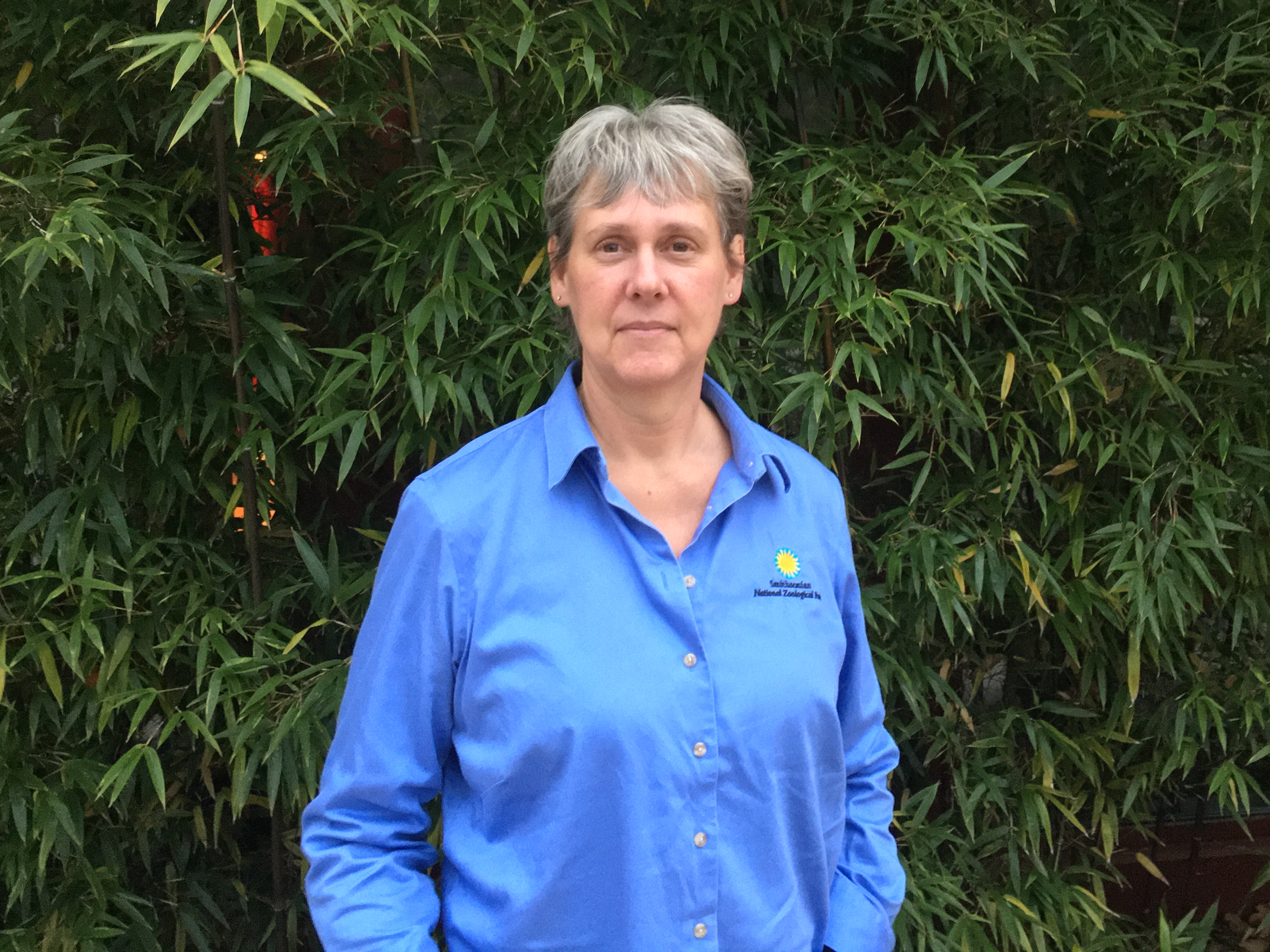 Sara Gallager in a blue shirt stands in front of bamboo.