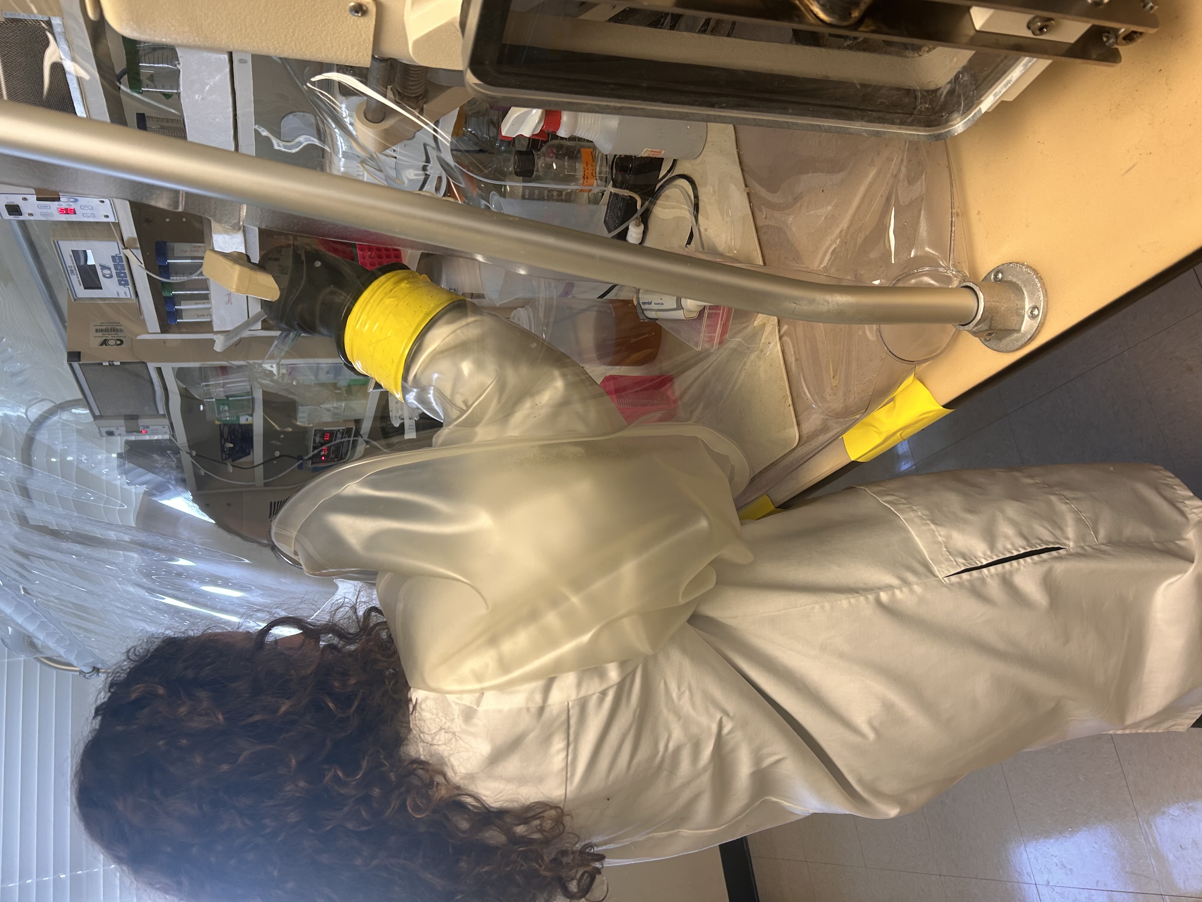 Woman working in the lab with her arm in a plastic sleeve.