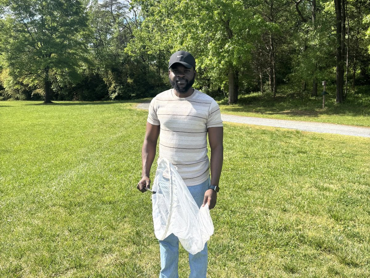 Michael posing for photo in field while holding a sweep net