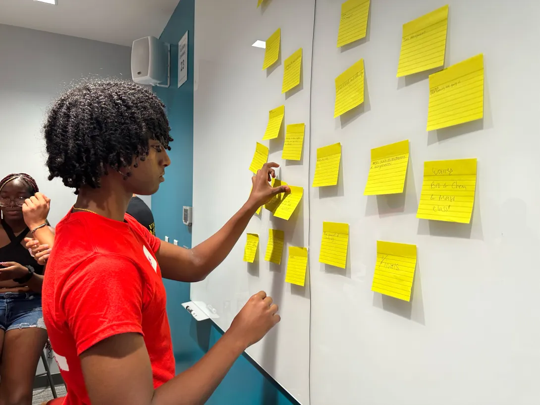 Student putting sticky notes on a whiteboard