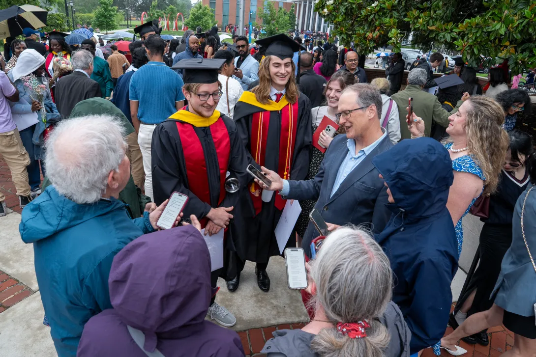 Graduates interacting with family members after commencement