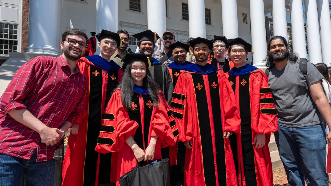 A large group of Ph.D. graduates and their friends celebrating in front of the armory.