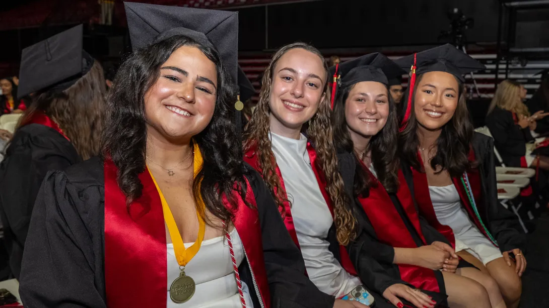 A group of young women in gratuation regalia at the Xfinity Center before the ceremony
